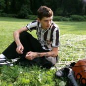 Musician Glaive sitting in front of football goals wearing a football top.